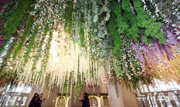 [부산=뉴시스] 하경민 기자 = 6일 부산 해운대구 신세계센텀시티 지하2층 중앙광장에 조성된 '하이퍼 가든'(Hyper Garden)을 찾은 시민들이 기념사진을 찍고 있다. 오는 5월까지 선보이는 하이퍼 가든은 '모네의 정원'을 테마로 수국, 등나무꽃, 델피늄 등의 화사한 꽃과 천장에서부터 내려오는 아치형 식물, 새 모형의 조명 등을 더해 봄 분위기를 연출했다. 2026.03.06. yulnetphoto@newsis.com