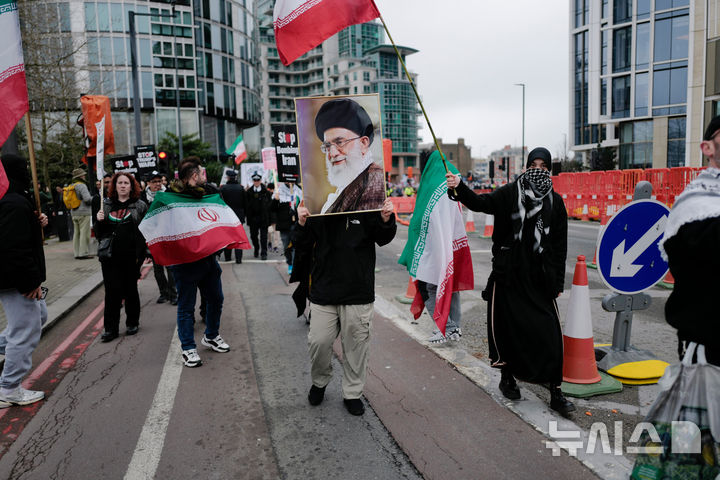 [런던=AP/뉴시스] 7일 영국 런던에서 이란 국기와 지난달 28일 미국과 이스라엘 공습으로 사망자 최고지도자 아야톨라 알리 하메네이의 사진을 든 시위대가 '전쟁 중단 연합' 행진을 벌이고 있다. 2026.03.08.&nbsp; 