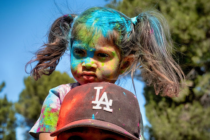 [로스앤젤레스=AP/뉴시스] 8일(현지 시간) 미 캘리포니아주 로스앤젤레스에서 열린 힌두교 색채 축제 '홀리'에 참여한 한 소녀가 색가루를 뒤집어쓴 채 아빠 어깨에 앉아 축제를 구경하고 있다. 2026.03.09.