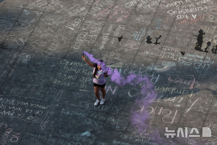 A protester lights a flare during a rally marking International Women's Day, at the Zocalo in Mexico City, Sunday, March 8, 2026. (AP Photo/Ginnette Riquelme)