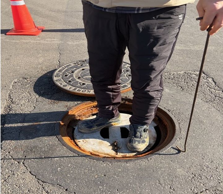 [광명=뉴시스] 경기 광명동 일원 맨홀에 설치된 추락방지시설. 설치자가 방지시설 위로 올라가 안정성을 시연하고 있다. (사진=광명시 제공) 2026.03.10. photo@newsis.com *재판매 및 DB 금지