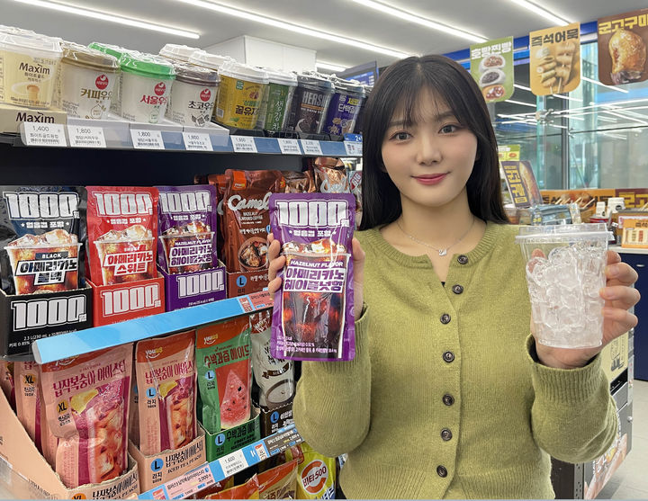 [서울=뉴시스] GS25에서 모델이 1천 원 아이스커피와 얼음컵을 들고 포즈를 취하고 있다 (사진=GS25 제공) 2026.03.12. photo@newsis.com *재판매 및 DB 금지