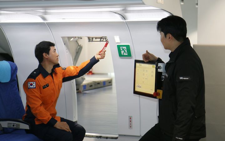 [부산=뉴시스] 지난 11일 에어부산 사옥 훈련시설에서 부산소방재난본부 소속 소방관들이 항공기 비상구 조작법을 배우고 있다. (사진=에어부산 제공) 2026.03.12. photo@newsis.com *재판매 및 DB 금지