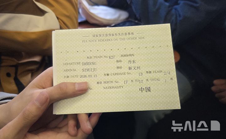 [베이징=뉴시스] 박정규 특파원 = 12일 중국 베이징에서 북·중 간 여객열차 운행이 재개된 가운데 이날 평양행 열차인 K27편에 탑승한 한 중국인 대학생이 목적지가 신의주라고 써있는 증서를 들어보이고 있다. 2026.03.13 pjk76@newsis.com