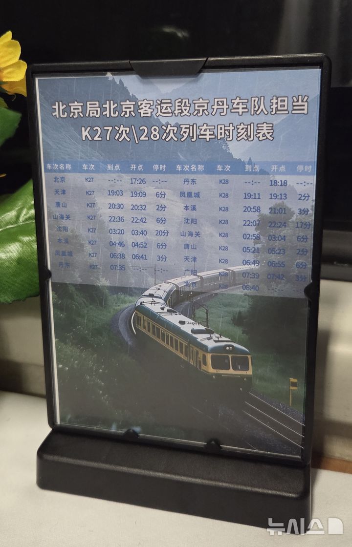 [베이징=뉴시스] 박정규 특파원 = 12일 북·중 간 여객열차 운행이 재개된 가운데 평양행 열차인 K27편 객실 내부 탁자에 중간 정착역과 시간표가 쓰인 안내판이 놓여있다. 2026.03.13 pjk76@newsis.com