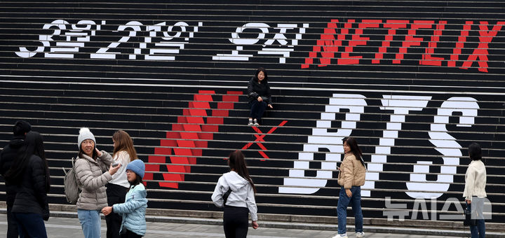 [서울=뉴시스] 추상철 기자 = 방탄소년단(BTS)의 서울 광화문광장 컴백 공연을 엿새 앞둔 15일 오후 서울 종로구 세종문화회관 계단에서 외국인관광객이 BTS 컴백 공연 관련 래핑 광고를 배경으로 기념촬영을 하고 있다. 2026.03.15. scchoo@newsis.com