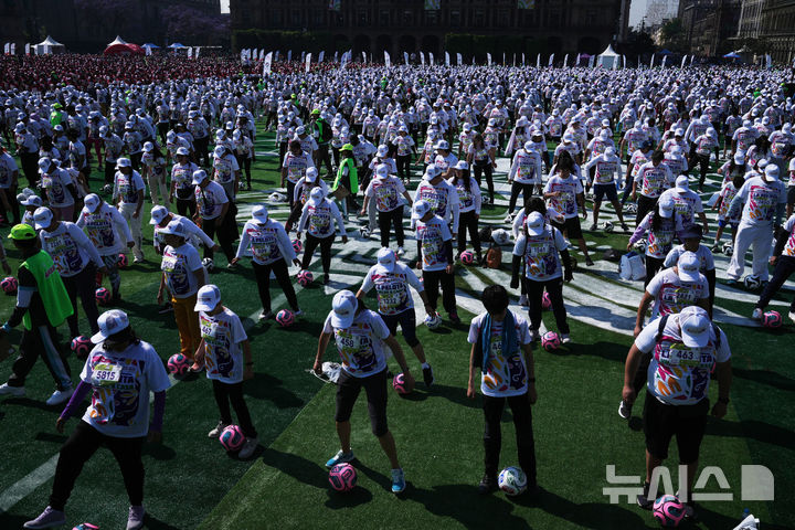 [멕시코시티=AP/뉴시스] 15일(현지 시간) 멕시코 수도 멕시코시티 소칼로 광장에서 열린 세계 최대 규모 축구 수업에 참여한 시민들이 기네스 세계 기록에 도전하고 있다. 2026.03.16.