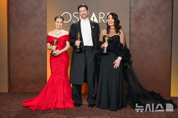[로스앤젤레스=AP/뉴시스] 매기 강(왼쪽부터) 감독, 크리스 아펠한스 공동 연출자, L.M.웡 프로듀서가 15일(현지 시간) 미 캘리포니아주 로스앤젤레스 돌비 극장에서 열린 제98회 아카데미 시상식에서 케이팝 데몬 헌터스(케데헌)로 장편 애니메이션상을 받은 후 프레스룸에서 포즈를 취하고 있다. 2026.03.16.