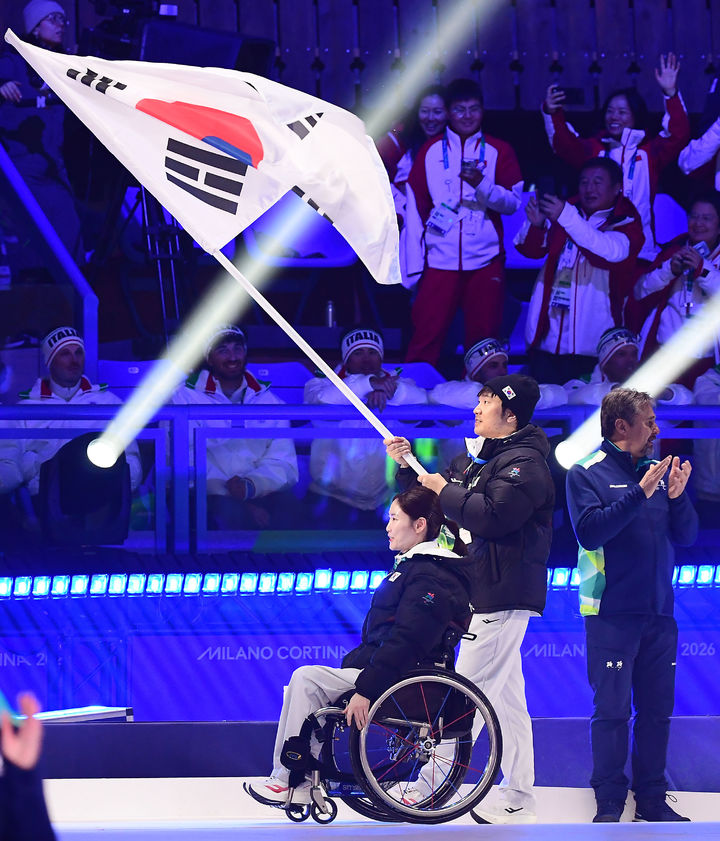 [서울=뉴시스] 사진공동취재단 = 14일(현지 시간) 이탈리아 코르티나담페초 코르티나 컬링 올림픽 스타디움에서 2026 밀라노·코르티나담페초 동계패럴림픽 폐회식에서 한국 선수단 기수를 맡은 휠체어컬링의 백혜진과 스노보드의 이제혁이 태극기를 들고 입장하고 있다. 2026.03.16 *재판매 및 DB 금지