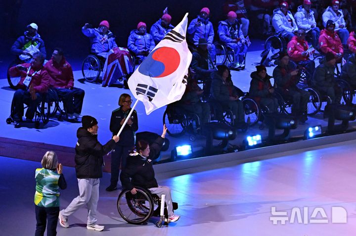 [코르티나담페초=뉴시스] 사진공동취재단 = 휠체어컬링 백혜진과 스노보드 이제혁이 15일(현지시간) 이탈리아 코르티나담페초 컬링 올림픽 스타디움에서 열린 2026 밀라노 코르티나담페초 패럴림픽 폐회식에서 태극기를 들고 입장하고 있다. 2026.03.16. photo@newsis.com