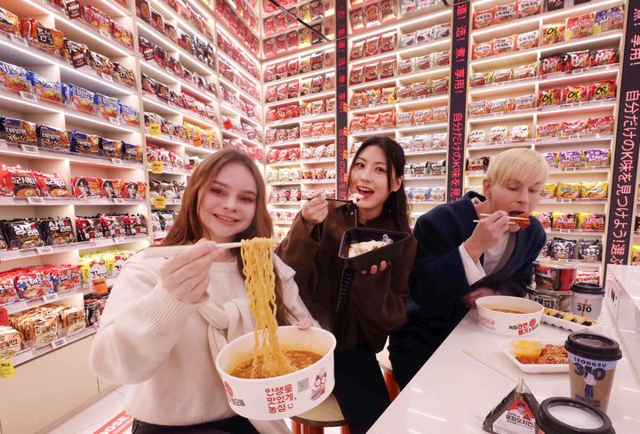 [서울=뉴시스] 이마트24 'K-푸드랩 명동점' 라면 아카이브 월 앞에서 모델들이 라면을 시식하고 있다.(사진=이마트24 제공) 2026.03.16. photo@newsis.com *재판매 및 DB 금지