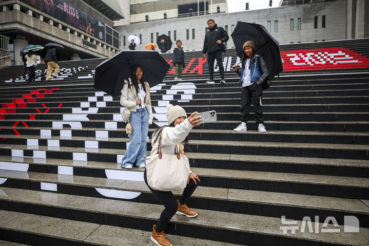 [서울=뉴시스] 정병혁 기자 = 방탄소년단(BTS)의 서울 광화문광장 컴백 공연을 앞둔 18일 서울 종로구 세종문화회관 계단을 찾은 외국인 팬들이 BTS 랩핑 앞에서 사진을 찍고 있다. 2026.03.18. jhope@newsis.com