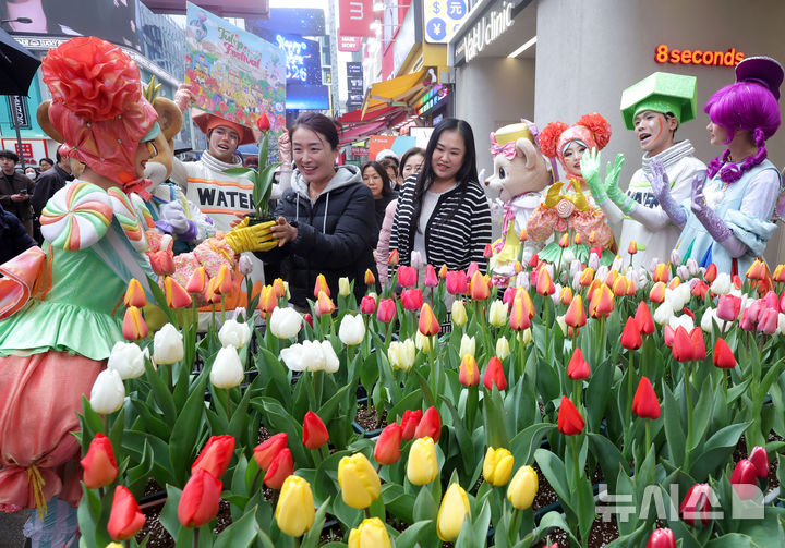 [서울=뉴시스] 홍효식 기자 = 18일 서울 중구 명동 일대 한 거리에서 열린 '도심에서 미리 만나는 에버랜드 튤립축제'에서 에버랜드 공연 연기자들이 시민들에게 튤립을 전달하고 있다.에버랜드는 오는 20일부터 '에버랜드 튤립축제'를 개최하며 튤립, 수선화, 무스카리 등 100여종 약 120만송이 형형색색 봄꽃을 선보인다. 2026.03.18. yesphoto@newsis.com
