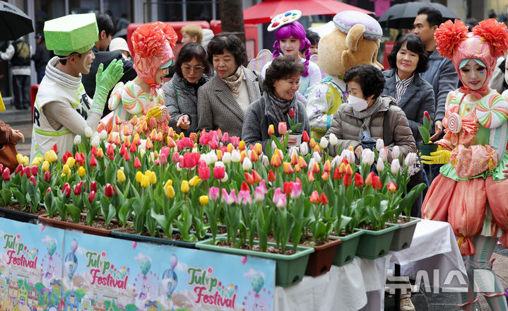 [서울=뉴시스] 홍효식 기자 = 18일 서울 중구 명동 일대 한 거리에서 열린 '도심에서 미리 만나는 에버랜드 튤립축제'에서 에버랜드 공연 연기자들이 시민들에게 튤립을 전달하고 있다.에버랜드는 오는 20일부터 '에버랜드 튤립축제'를 개최하며 튤립, 수선화, 무스카리 등 100여종 약 120만송이 형형색색 봄꽃을 선보인다. 2026.03.18. yesphoto@newsis.com