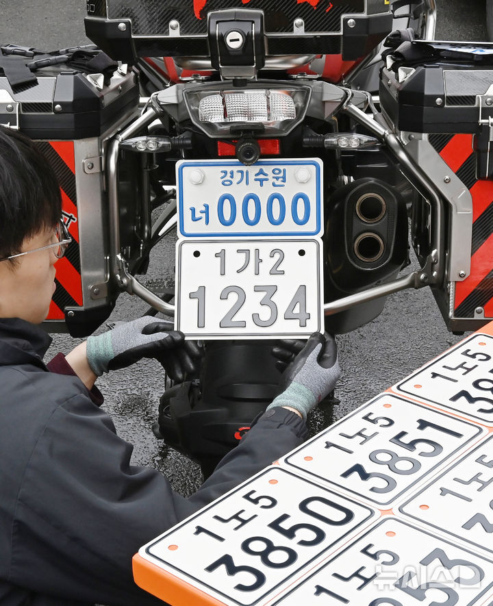 [수원=뉴시스] 김종택 기자 = 이륜자동차 전국 번호판 제도 시행을 이틀 앞둔 18일 경기 수원시 권선구 수원시번호판제작소에서 관계자가 새롭게 도입된 이륜차 번호판(사진 아래)을 시연하고 있다.이번에 도입된 이륜차 번호판 규격은 기존 210㎜115㎜에서 210㎜150㎜로 확대됐다. 글자 색상도 파란색에서 검은색으로 변경, 반사 성능이 강화된 재질이 적용돼 주·야간 식별성이 개선됐다. 2026.03.18. jtk@newsis.com