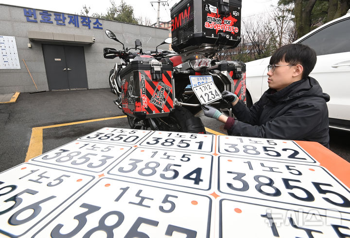 [수원=뉴시스] 김종택 기자 = 이륜자동차 전국 번호판 제도 시행을 이틀 앞둔 18일 경기 수원시 권선구 수원시번호판제작소에서 관계자가 새롭게 도입된 이륜차 번호판을 시연하고 있다.이번에 도입된 이륜차 번호판 규격은 기존 210㎜115㎜에서 210㎜150㎜로 확대됐다. 글자 색상도 파란색에서 검은색으로 변경, 반사 성능이 강화된 재질이 적용돼 주·야간 식별성이 개선됐다. 2026.03.18. jtk@newsis.com