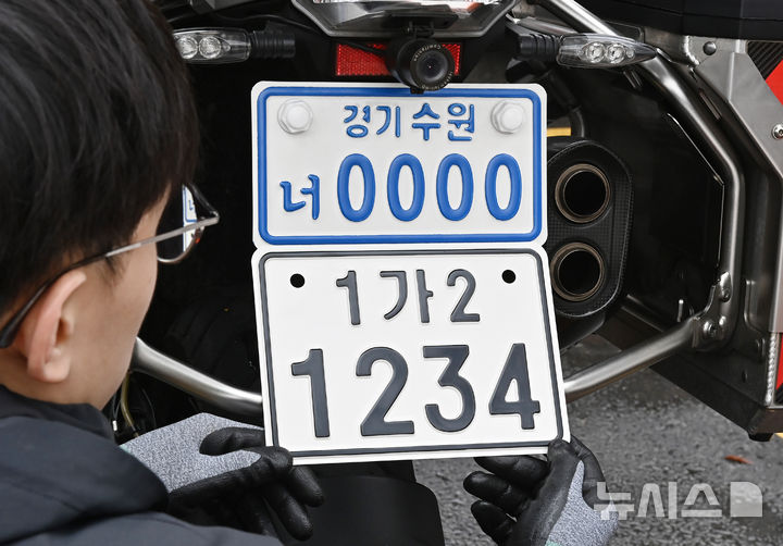 [수원=뉴시스] 김종택 기자 = 이륜자동차 전국 번호판 제도 시행을 이틀 앞둔 18일 경기 수원시 권선구 수원시번호판제작소에서 관계자가 새롭게 도입된 이륜차 번호판(사진 아래)을 시연하고 있다.이번에 도입된 이륜차 번호판 규격은 기존 210㎜115㎜에서 210㎜150㎜로 확대됐다. 글자 색상도 파란색에서 검은색으로 변경, 반사 성능이 강화된 재질이 적용돼 주·야간 식별성이 개선됐다. 2026.03.18. jtk@newsis.com