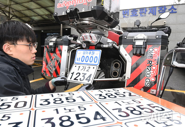 [수원=뉴시스] 김종택 기자 = 이륜자동차 전국 번호판 제도 시행을 이틀 앞둔 18일 경기 수원시 권선구 수원시번호판제작소에서 관계자가 새롭게 도입된 이륜차 번호판을 시연하고 있다.이번에 도입된 이륜차 번호판 규격은 기존 210㎜115㎜에서 210㎜150㎜로 확대됐다. 글자 색상도 파란색에서 검은색으로 변경, 반사 성능이 강화된 재질이 적용돼 주·야간 식별성이 개선됐다. 2026.03.18. jtk@newsis.com