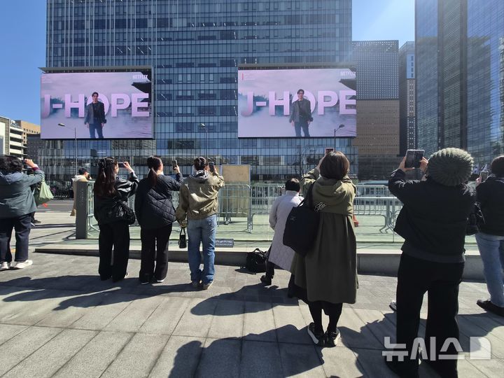 [서울=뉴시스]조수원 기자=19일 오전 광화문 일대에 설치된 전광판에 나오는 아이돌 그룹 방탄소년단(BTS) 광고를 관광객들이 촬영하고 있다. 2026.03.19 tide1@newsis.com