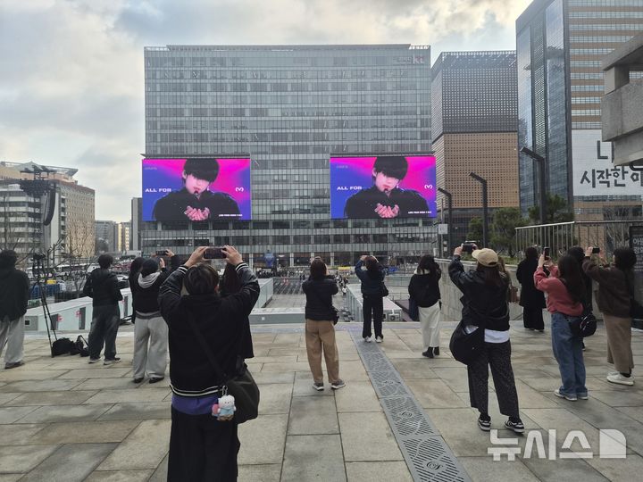 [서울=뉴시스]조수원 기자=BTS 컴백 공연을 하루 앞둔 20일 오전 서울 종로구 광화문광장 인근 KT 건물 전광판에 BTS 슈가 광고 영상이 나오자 관광객들이 스마트폰을 들어 촬영하고 있다. 2026.03.20. tide1@newsis.com