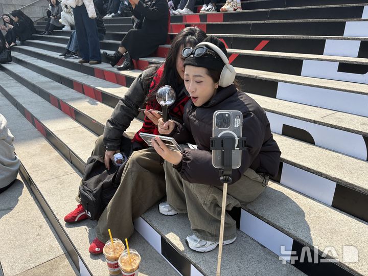 [서울=뉴시스]신유림 기자=BTS의 광화문 공연을 하루 앞둔 20일 오후, 서울 종로구 세종문화회관 계단에서 베트남 팬 지아(23·왼쪽) 씨와 민(32·오른쪽)씨가 이날 공개된 신곡 'SWIM'의 뮤직비디오를 보며 환호하고 있다. 2026.03.20. spicy@newsis.com