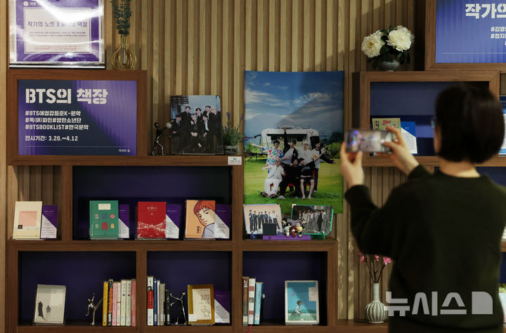 [서울=뉴시스] 이영환 기자 = 방탄소년단(BTS)이 완전체로 컴백하는 20일 오전 서울 서초구 국립중앙도서관 지식의 길에 마련된 BTS의 책장에서 한 시민이 BTS 멤버의 추천 도서를 휴대전화에 담고 있다. 방탄소년단은 이날 오후 1시 정규 5집 '아리랑'을 발매하며 국립중앙도서관 지식의 길에 마련된 BTS의 책장은 내달 12일까지 열린다. 전시 도서에는 한강의 '소년이 온다', 이민진의 '파친코', 손원평의 '아몬드', 김애란의 '비행운' 등의 소설이 배치된다. 또 윤동주의 '하늘과 별과 바람과 시' 초판본, 백석의 '사슴' 초판본, 나태주의 '꽃을 보듯 너를 본다' 등 시도 함께 전시된다. 2026.03.20. 20hwan@newsis.com