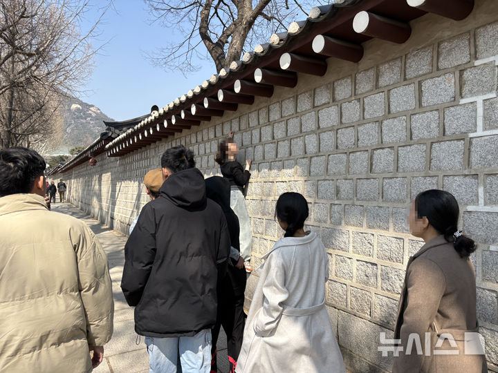 [서울=뉴시스] 한이재 기자 = 21일 방탄소년단 복귀 공연에 차도와 인도 통제가 이뤄지는 가운데 한 여성이 경복궁 담벼락을 오르다 공무원에게 제지당했다. 2026.03.21. nowone@newsis.com