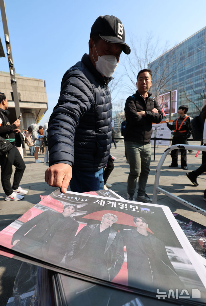 [서울=뉴시스] 권창회 기자 = 방탄소년단(BTS) 컴백 공연 당일인 21일 서울 종로구 광화문광장에서 시민들이 주요 일간지들이 발행한 BTS 관련 호외를 챙기고 있다. 2026.03.21. kch0523@newsis.com