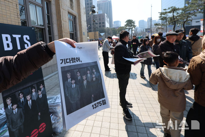 [서울=뉴시스] 권창회 기자 = 방탄소년단(BTS) 컴백 공연 당일인 21일 서울 종로구 광화문광장 일대에서 주요 일간지들이 발행한 BTS 관련 호외를 관계자가 배포하고 있다. 2026.03.21. kch0523@newsis.com