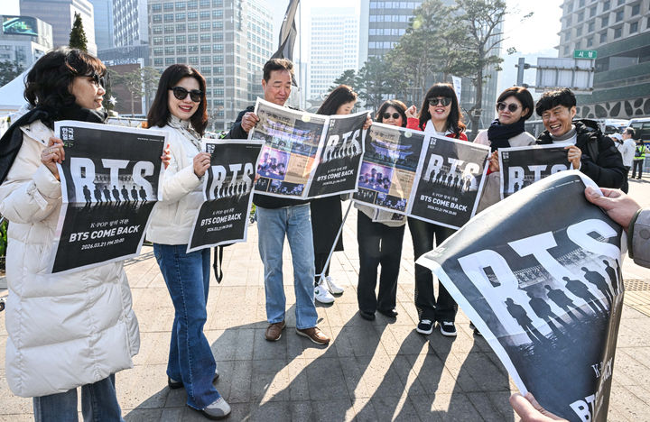 [서울=뉴시스] 그룹 방탄소년단(BTS) 컴백 공연을 앞둔 21일 서울 광화문 일대에서 일본인 관광객들이 한국일보가 발행한 BTS 특별판을 받아 보고 있다. (사진=한국일보 제공) 2026.03.21. photo@newsis.com *재판매 및 DB 금지