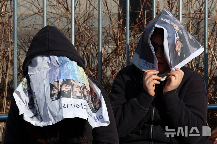 [서울=뉴시스] 조성우 기자 = 방탄소년단(BTS) 컴백 공연 당일인 21일 서울 종로구 광화문광장에서 팬들이 BTS 기념 호외로 햇볕을 막고 있다. 2026.03.21. xconfind@newsis.com