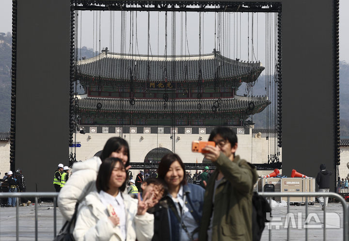 [서울=뉴시스] 김근수 기자 = 22일 오전 서울 종로구 광화문광장에서 전날 열린 방탄소년단의 'BTS 컴백 라이브 : 아리랑' 공연 무대 철거작업이 진행되는 가운데 외국인 관광객들이 기념촬영을 하고 있다. 2026.03.22. ks@newsis.com