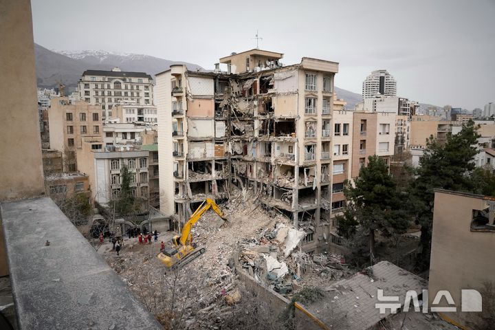 [AP/뉴시스] 23일 이란 테헤란에서 미-이스라엘의 초기 공격 때 파괴된 거주지 건물을 이란 적신월사 요원들이 불도저로 잔해 정리하고 있다