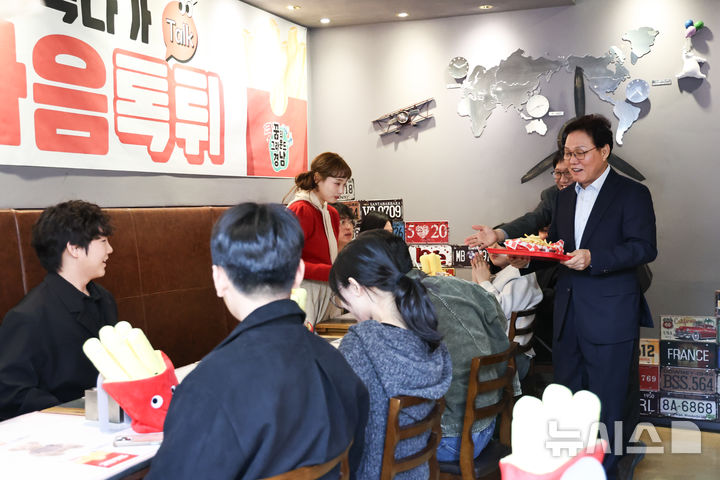 [창원=뉴시스]박완수 경남도지사가 23일 오후 늦은 시각 창원 가로수길의 한 햄버거 매장에서 청년들과의 소통 간담회에 앞서 감자튀김을 서빙하고 있다.(사진=경남도 제공) 2026.03.23. photo@newsis.com