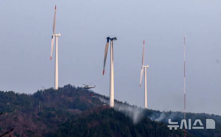 [영덕=뉴시스] 이무열 기자 = 23일 오후 1시 11분께 경북 영덕군 한 풍력발전단지 내 풍력발전기에서 화재가 발생해 출동한 헬기가 발전기와 주변으로 번진 불길을 진압하기 위해 물을 뿌리고 있다. 이 사고로 정비 작업자 3명이 숨졌다. 2026.03.23. lmy@newsis.com