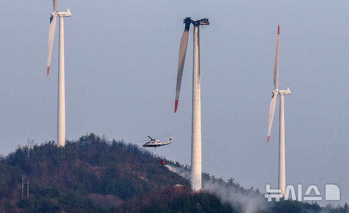 [영덕=뉴시스] 이무열 기자 = 지난 23일 오후 1시 11분께 경북 영덕군 한 풍력발전단지 내 풍력발전기에서 화재가 발생해 출동한 헬기가 발전기와 주변으로 번진 불길을 진압하기 위해 물을 뿌리고 있다. 이 사고로 정비 작업자 3명이 숨졌다. 2026.03.23. lmy@newsis.com