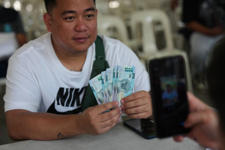 [케손시티=AP/뉴시스] 24일(현지 시간) 필리핀 케손시티에서 교통네트워크차량서비스(TNVS) 운전자들이 정부로부터 생계 지원 현금을 받고 있다. 필리핀 정부는 유가 상승에 대응하기 위해 일부 정부 기관 직원들에게 최소 주 1회 재택근무를 의무화하고, 비필수 출장도 금지했으며 삼륜차 운전자, 농민, 어민들에게 현금을 지원하고 있다. 2026.03.24.