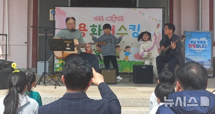 [영동=뉴시스] 충북 영동 용화초등학교가 24일 점심시간을 이용해 중앙현관 특설무대에서 ‘봄꽃 버스킹’ 공연을 하고 있다. 병설유치원 원아들의 노래, 2~3학년생의 댄스공연, 3~4학년생의 리코더 연주, 5~6학년생과 김은주 교사의 노래 공연을 진행했다. (사진=영동교육지원청 제공) 2026.03.24. photo@newsis.com *재판매 및 DB 금지