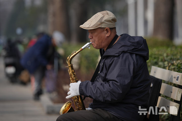 [베이징=AP/뉴시스] 지난 3월 25일 중국 베이징의 한 공원에서 노인이 색소폰을 연주하고 있다. 2026.10.29