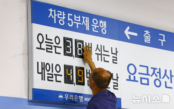 [서울=뉴시스] 김근수 기자 = 공공부문 승용차 5부제 의무화 첫날이자 금융업계도 차량 5부제 운행에 동참한 가운데 25일 오전 서울 중구 우리은행 본점 주차장에서 한 주차 안내원이 숫자를 조정하고 있다. 2026.03.25. ks@newsis.com