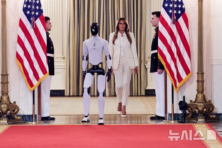 [워싱턴=AP/뉴시스] 도널드 트럼프 미국 대통령 부인 멜라니아 여사가 25일(현지 시간) 백악관에서 열린 ‘함께 미래 키우기' 글로벌 정상회의에 참석해 미국 제조 휴머노이드 로봇 '피겨3'과 함께 입장하고 있다. 2026.03.26.