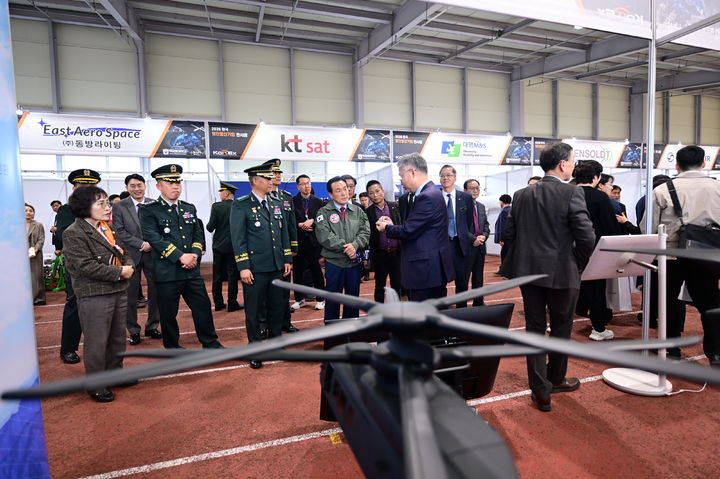 [논산=뉴시스] 백성현 충남 논산시장이 논산딸기축제와 함께 열리고 있는 '한국 회전익기(헬기) 전시회(KoREx)'에서 항공학교 관계자로부터 설명을 듣고 있다. (사진=논산시 제공) 2026.03.28. photo@newsis.com *재판매 및 DB 금지