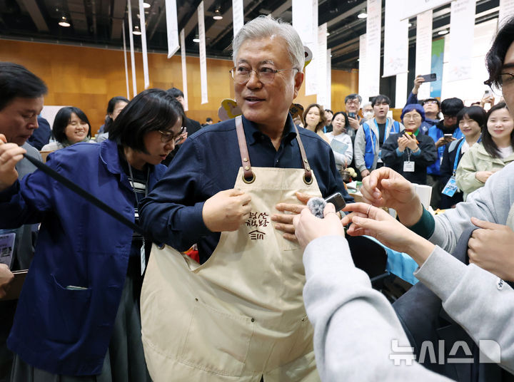 [파주=뉴시스] 이영환 기자 = 문재인 전 대통령이 28일 오후 경기 파주시 아시아출판정보문화센터 지혜의숲 다목적홀에서 열린 DMZ세계문학페스타 2026 북페어 '사이에서' 평산책방 부스에서 앞치마를 착용하고 있다. 2026.03.28. 20hwan@newsis.com