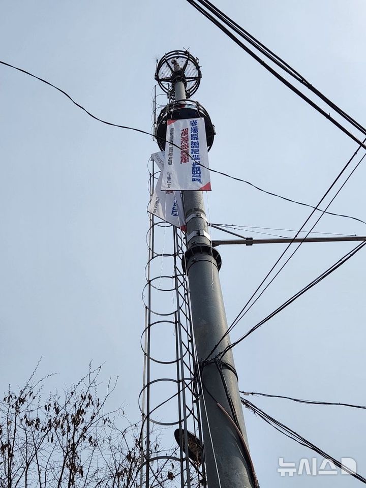 [서울=뉴시스] 민주노총 공공운수노조 택시지부 전북지회 대림교통분회장 고영기씨가 29일 인천 남동구 맹성규 국회 국토교통위원장 지역사무실 앞 20m 높이 통신탑에 올라 고공농성에 돌입했다. (사진=택시지부 제공) 2026.03.29. photo@newsis.com 