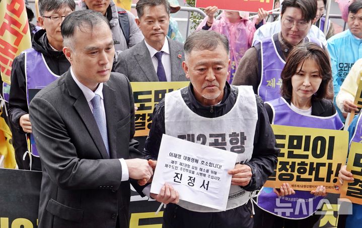 [제주=뉴시스] 오영재 기자 = 이재명 대통령 타운홀미팅이 예정된 30일 오후 제주시 한라컨벤션센터 앞에서 제주 제2공항 반대 단체인 제주제2공항강행저지비상도민회의가 유성우 대통령직속 지방시대위원회 총괄기획과장에게 제2공항 관련 진정서를 전달하고 있다. 2026.03.30. oyj4343@newsiscom 