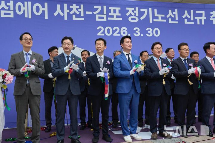 [사천=뉴시스]김경수(앞줄 왼쪽서 두 번째) 더불어민주당 경남도지사 후보가 30일 사천공항에서 열린 섬에어 사천~김포 정기노선 신규 취항식에 참석해 기념 테이프를 자른 후 박수치고 있다.(사진=김경수 후보 선거사무소 제공)2026.03.30. photo@newsis.com