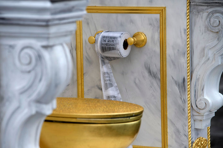 [워싱턴=AP/뉴시스] 30일(현지 시간) 미국 워싱턴DC 내셔널 몰에 설치된 ‘왕에게 어울리는 왕좌'(A throne fit for a king)라는 제목의 황금 변기 옆에 '시크릿 핸드셰이크'가 인쇄된 두루마리 화장지가 걸려 있다. 이 변기는 게릴라 예술그룹 '시크릿 핸드셰이크'가 만든 것으로 백악관 리모델링에 집착하는 도널드 트럼프 대통령을 조롱하는 작품이다. 2026.03.31.