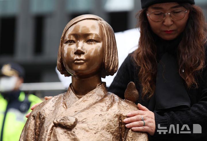 [서울=뉴시스] 김진아 기자 = 1일 서울 종로구 옛 주한 일본대사관 앞에서 열린 제1746차 일본군 성노예제 문제해결을 위한 정기 수요시위에서 한 참가자가 소녀상을 어루만지고 있다. 평화의 소녀상은 이날 수요시위에서 약 6년 만에 경찰 바리케이드를 벗어나 시민들 앞에 모습을 드러냈다. 안전 문제를 고려해 전면 철거 대신 한시 개방 방식을 택한 것으로 전해졌다. 경찰은 4월 말께 바리케이드 철거 여부를 다시 판단할 방침이다. 2026.04.01. bluesoda@newsis.com
