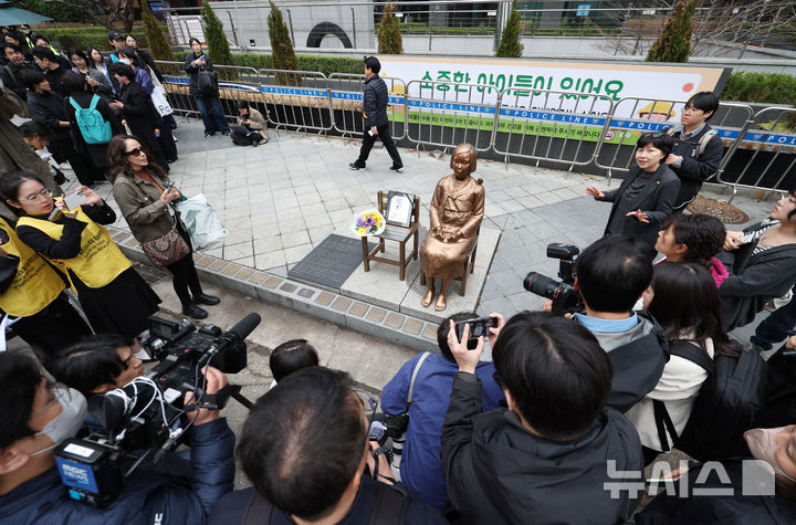 [서울=뉴시스] 김진아 기자 = 1일 서울 종로구 옛 주한 일본대사관 앞에서 열린 제1746차 일본군 성노예제 문제해결을 위한 정기 수요시위에서 참가자들이 소녀상과 사진을 찍고 있다. 평화의 소녀상은 이날 수요시위에서 약 6년 만에 경찰 바리케이드를 벗어나 시민들 앞에 모습을 드러냈다. 안전 문제를 고려해 전면 철거 대신 한시 개방 방식을 택한 것으로 전해졌다. 경찰은 4월 말께 바리케이드 철거 여부를 다시 판단할 방침이다. 2026.04.01. bluesoda@newsis.com
