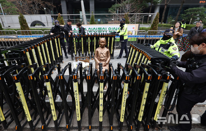[서울=뉴시스] 김진아 기자 = 1일 서울 종로구 옛 주한 일본대사관 앞에서 열린 제1746차 일본군 성노예제 문제해결을 위한 정기 수요시위에서 경찰들이 집회 끝난 뒤 소녀상 주위에 바리케이드를 설치하고 있다. 평화의 소녀상은 이날 수요시위에서 약 6년 만에 경찰 바리케이드를 벗어나 시민들 앞에 모습을 드러냈다. 안전 문제를 고려해 전면 철거 대신 한시 개방 방식을 택한 것으로 전해졌다. 경찰은 4월 말께 바리케이드 철거 여부를 다시 판단할 방침이다. 2026.04.01. bluesoda@newsis.com